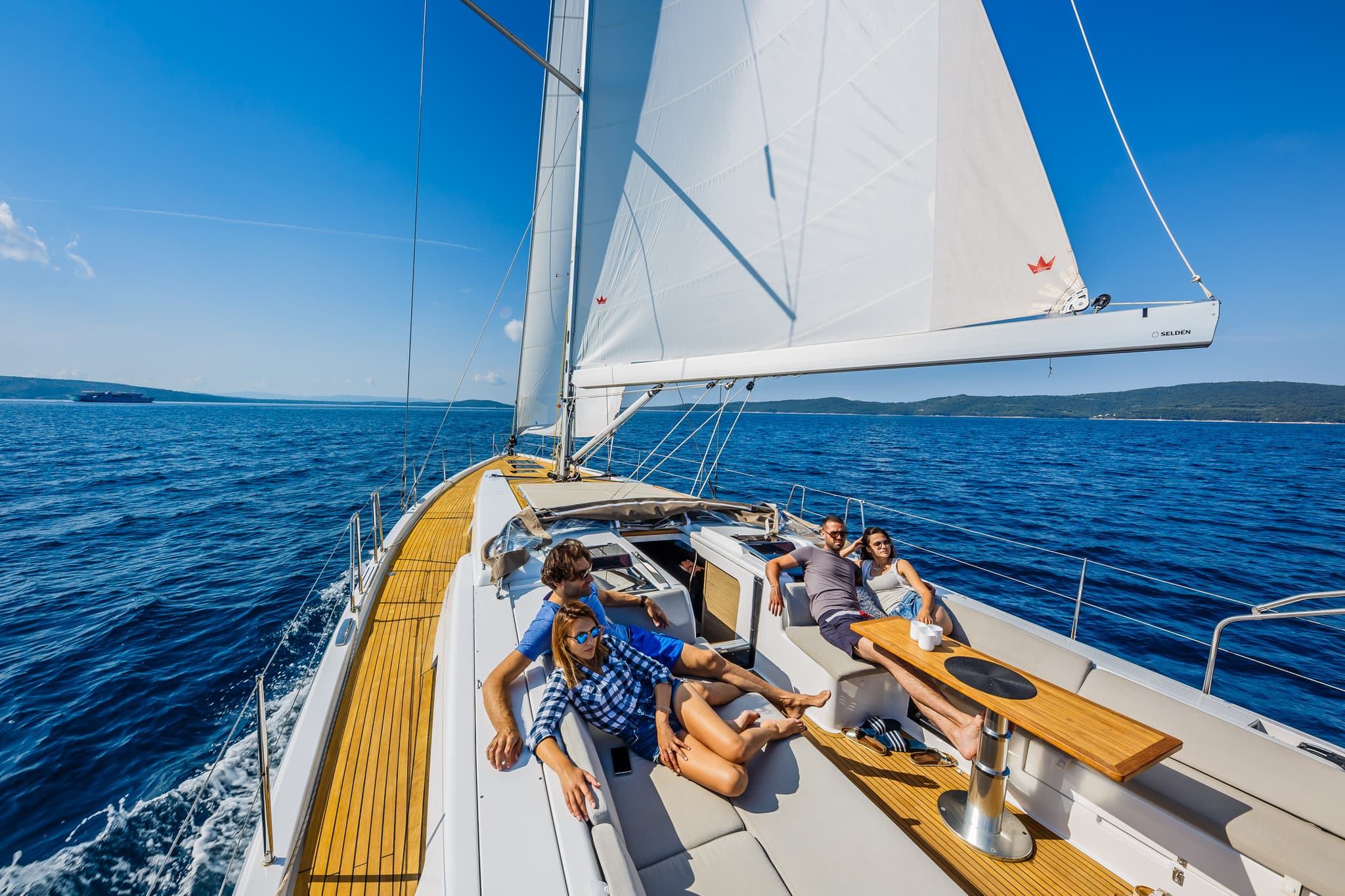People enjoying a sunny day on a Hanse sailboat with open sails on blue water