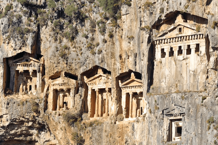 Ancient rock-cut tombs embedded in a cliff face, reflecting historical architecture and craftsmanship