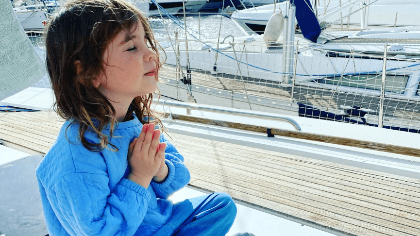 Child sitting on a Hanse 445 sailboat yacht deck with marina background